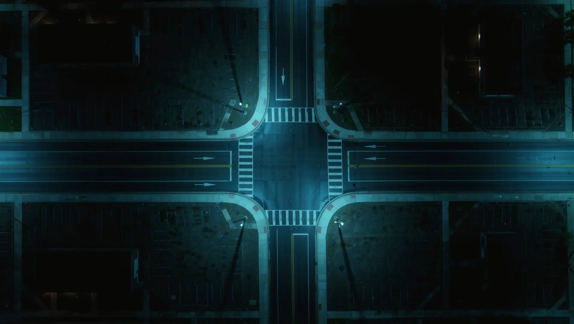 Night aerial view of a small-town crossroads with four corner lots